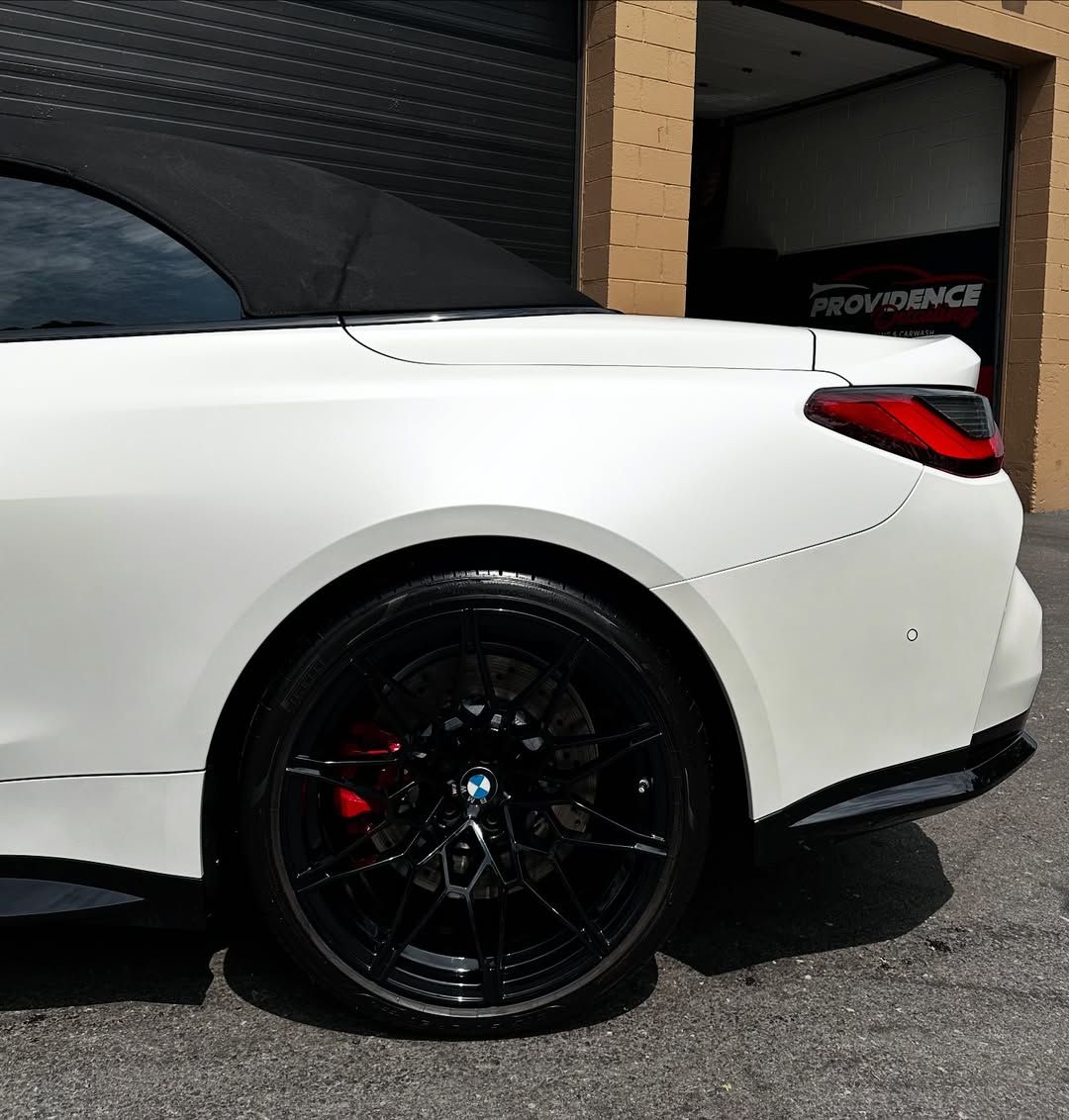A white sports car is parked in front of a garage