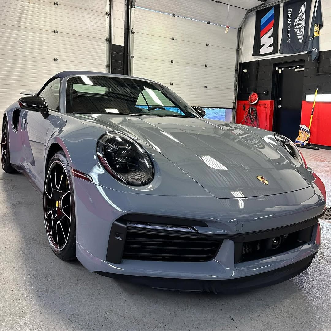 A gray porsche 911 carrera is parked in a garage.