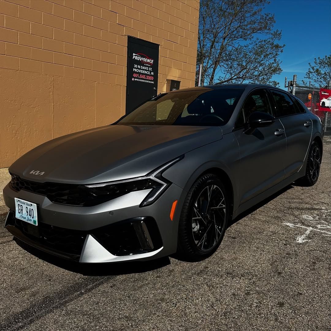 A gray car is parked in front of a brick building.