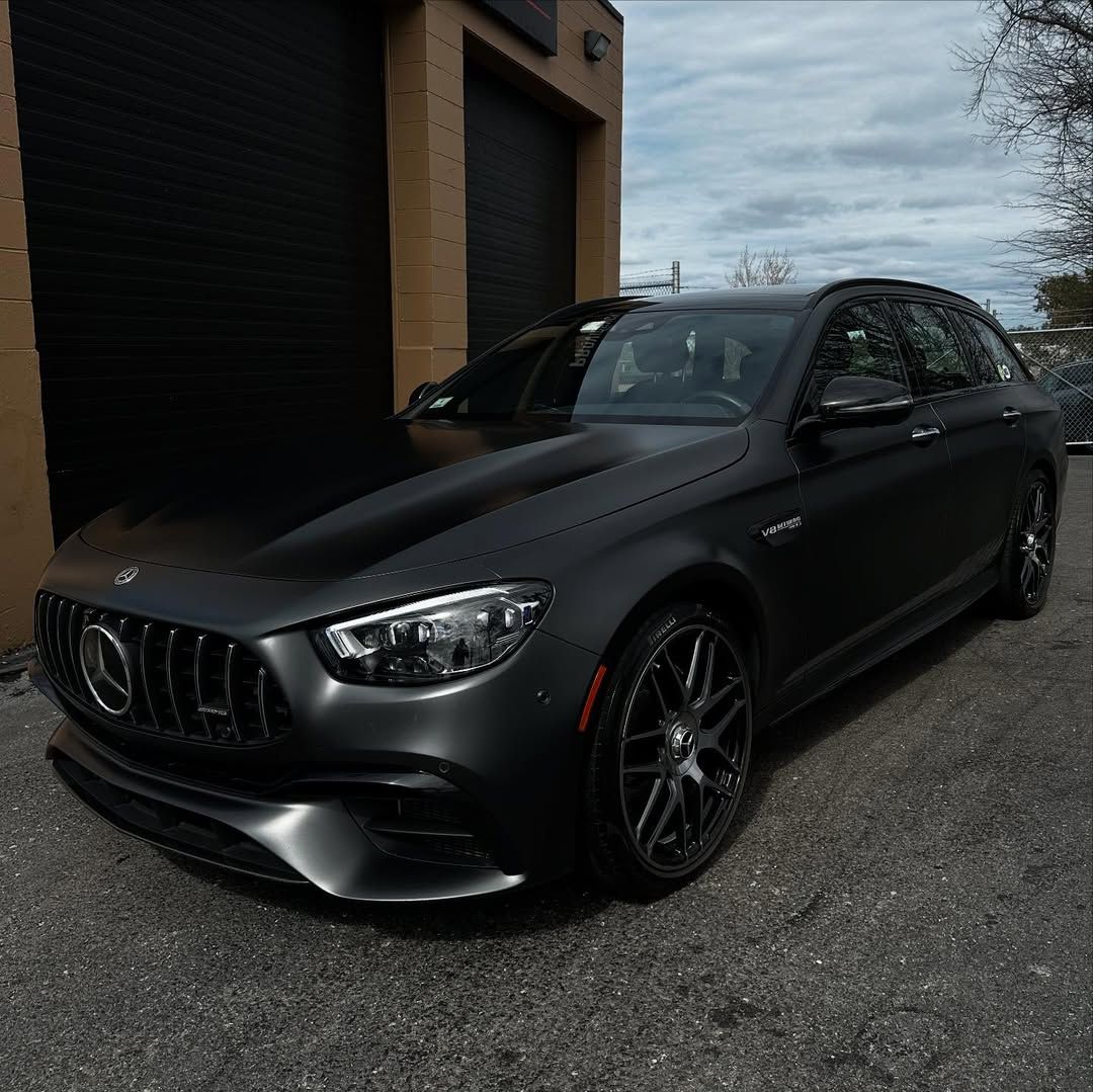 A black car is parked in front of a garage door.