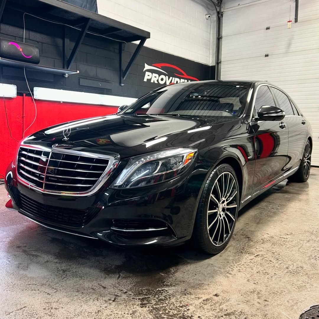 A black mercedes benz s class is parked in a garage.