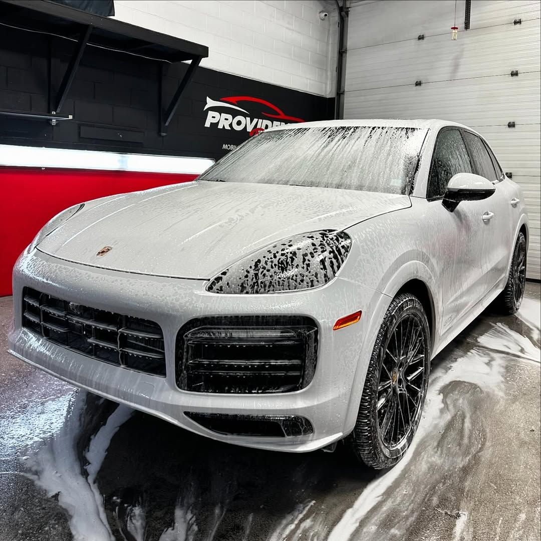 A white porsche cayenne is sitting in a garage covered in foam.