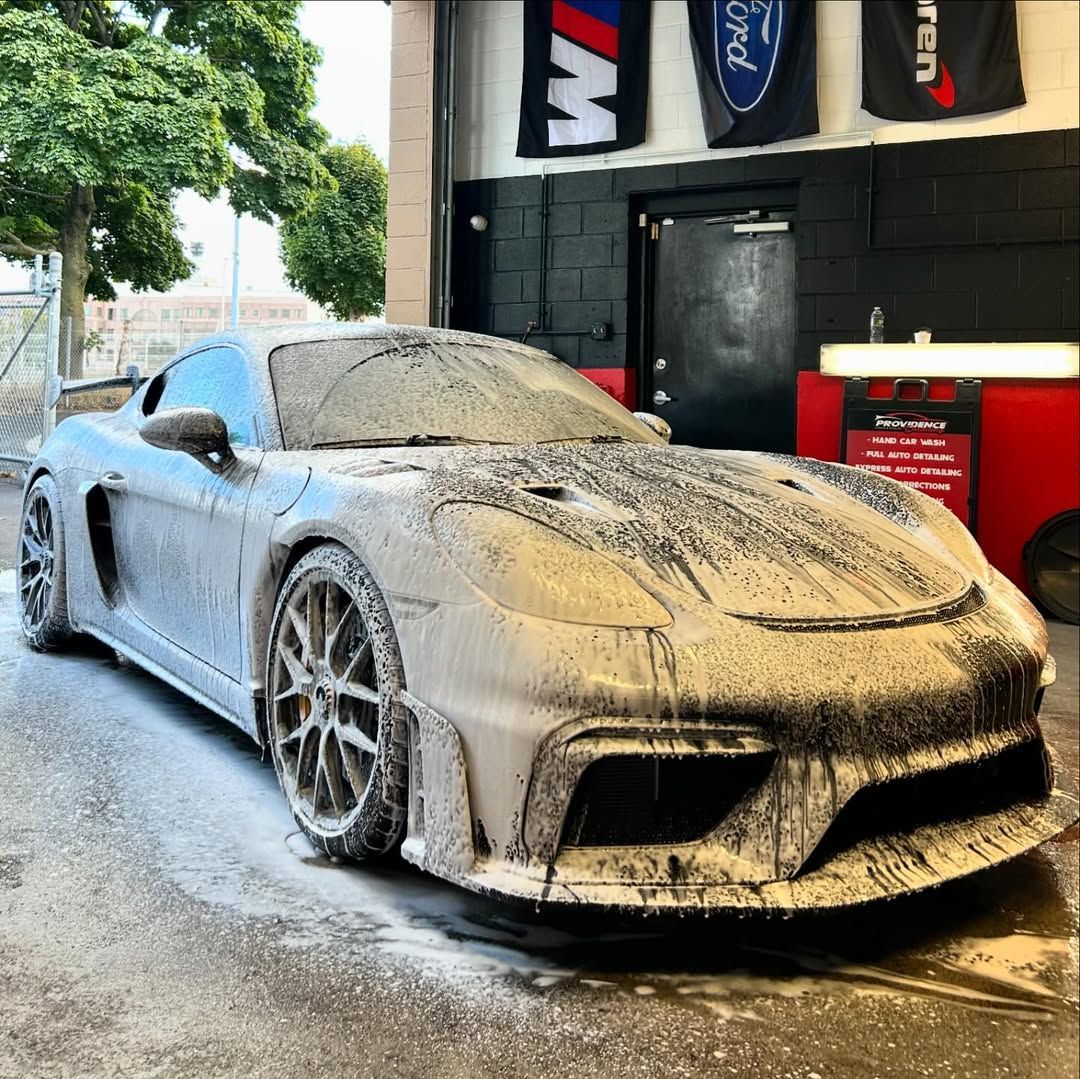 A muddy sports car is parked in front of a garage.