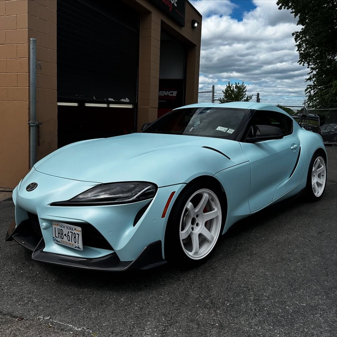 A light blue sports car is parked in front of a garage