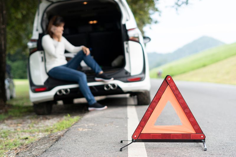 A woman is calling emergency services to help her with a broken car.