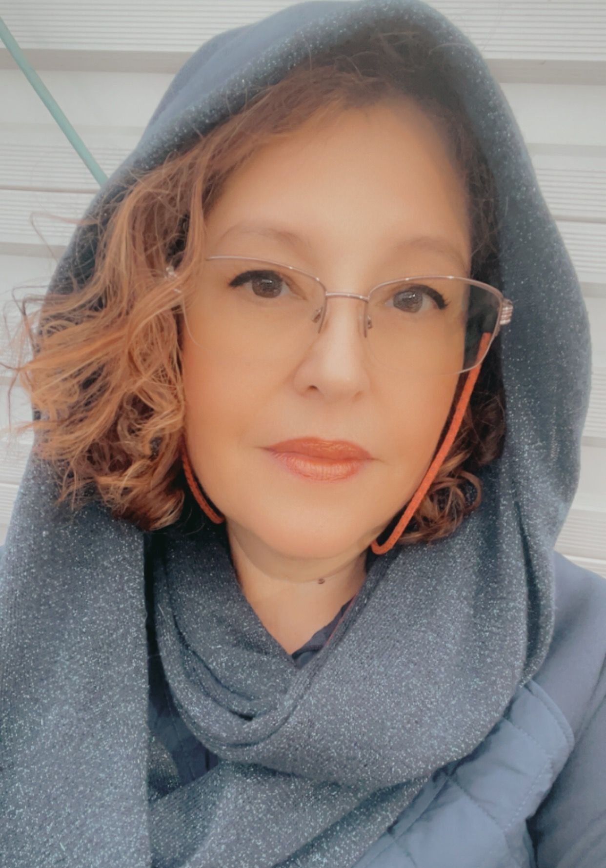 A woman wearing glasses and a scarf is taking a selfie.