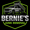 A logo for Bernie’s Junk Removal featuring a silver dump truck inside a green shield outline on a black background.
