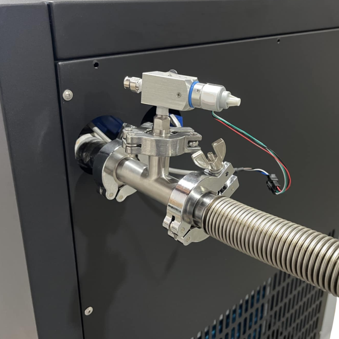 Metal tubing and valve attached to a dark machine. Wires and a silver hose protrude.