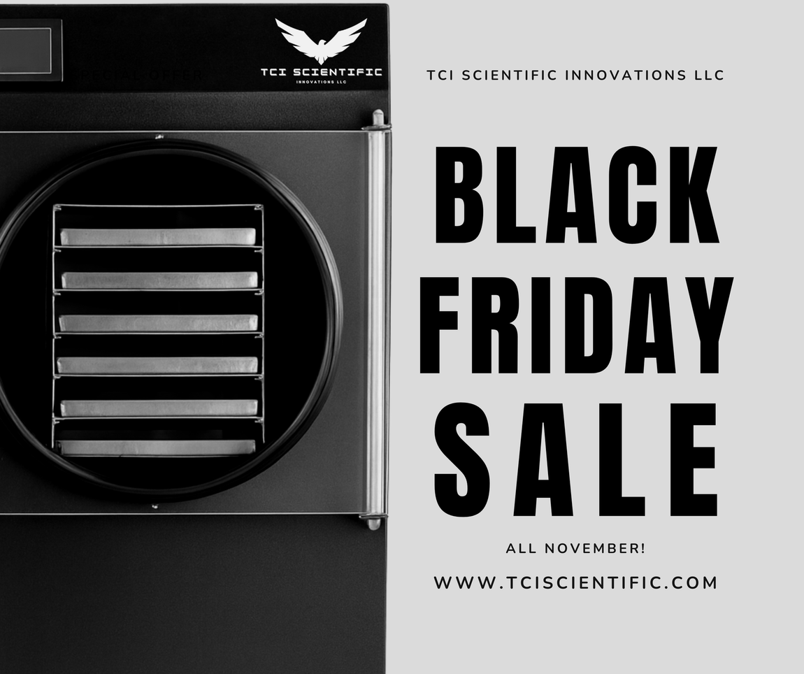 Black freeze dryer with vacuum pump connected, holding trays inside a cylindrical chamber.