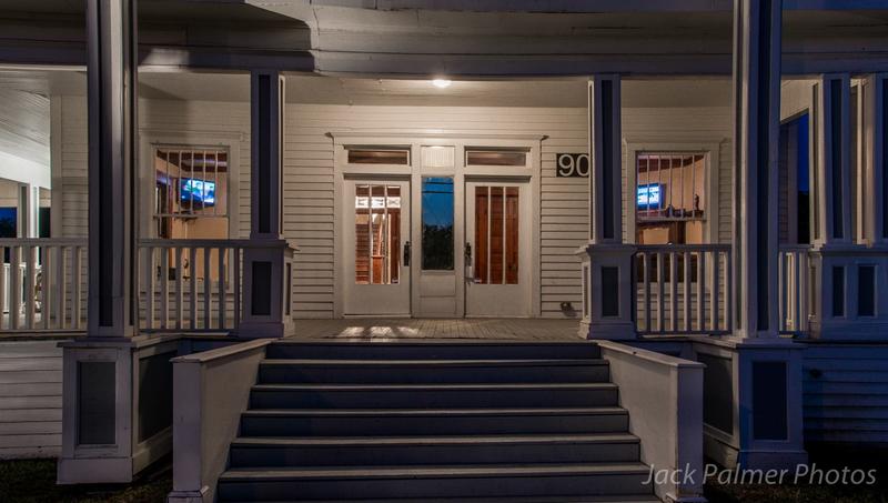 A white house with a porch and stairs at night.