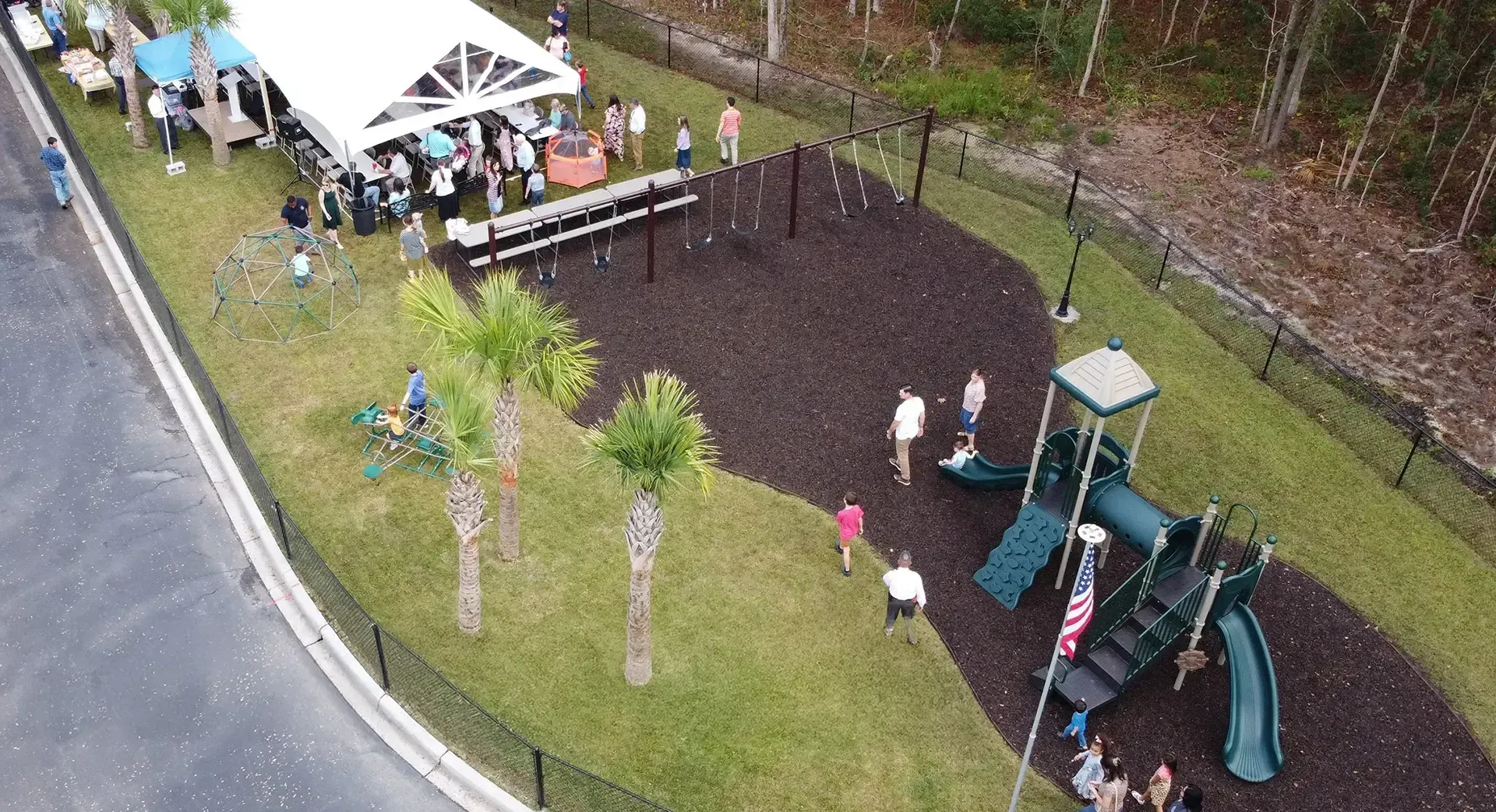 Aerial view of a playground with a tent, people, and equipment.