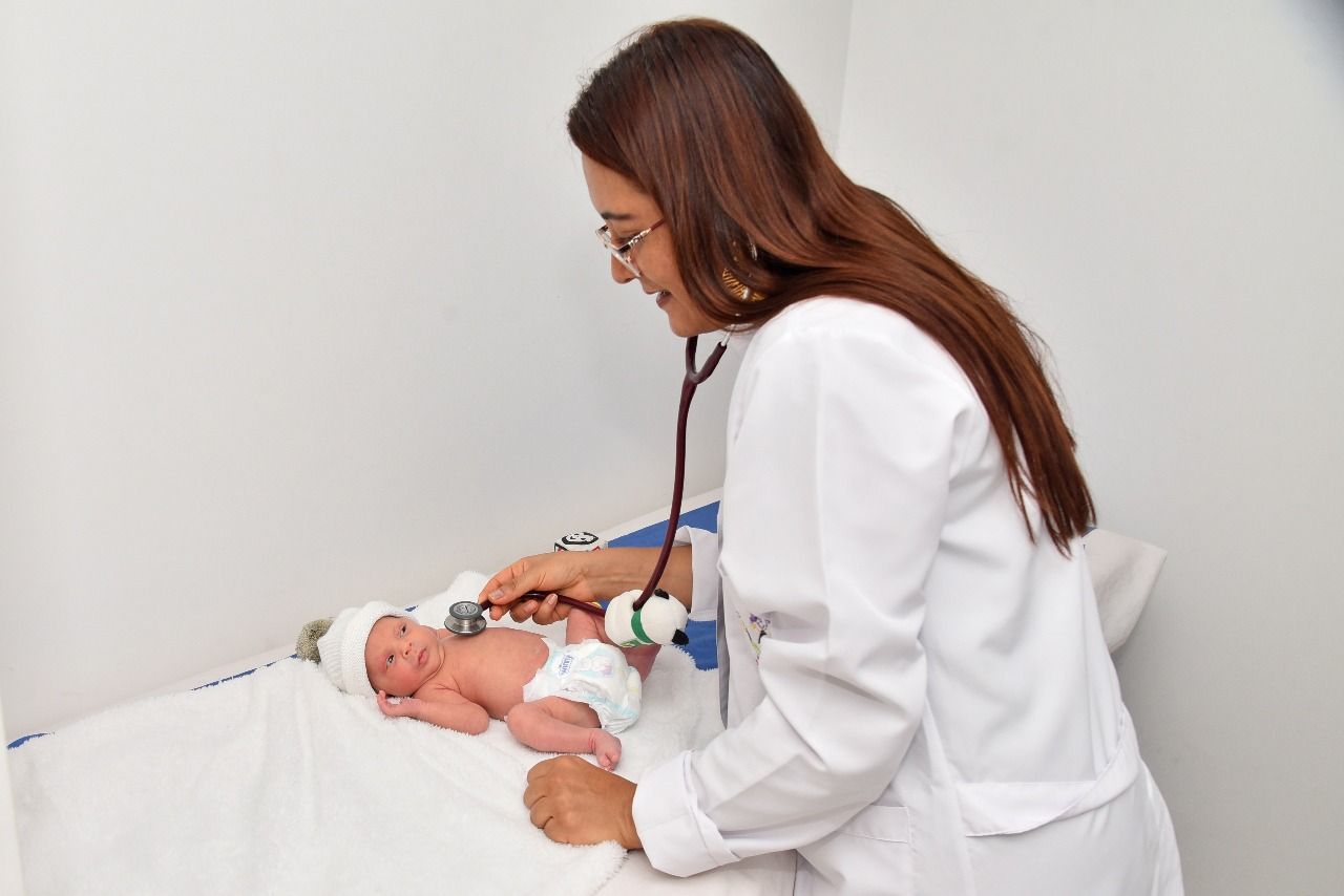 Una niña está sentada en una cama hablando por un teléfono rosa.