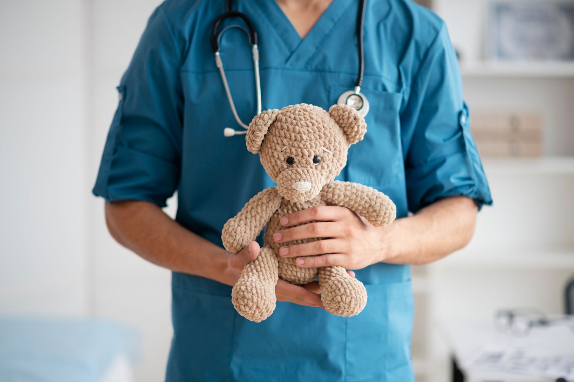 Un médico sostiene un osito de peluche en sus manos.