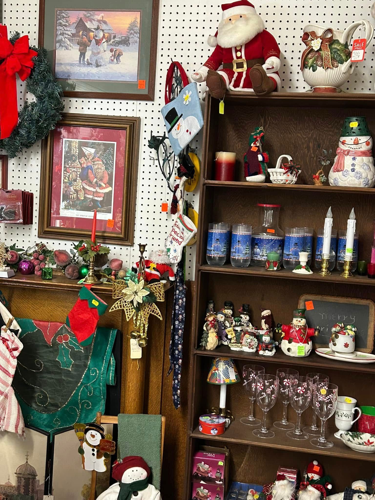 Holiday-decorated shelf and wall display with framed art, stockings, figurines, and festive ornaments