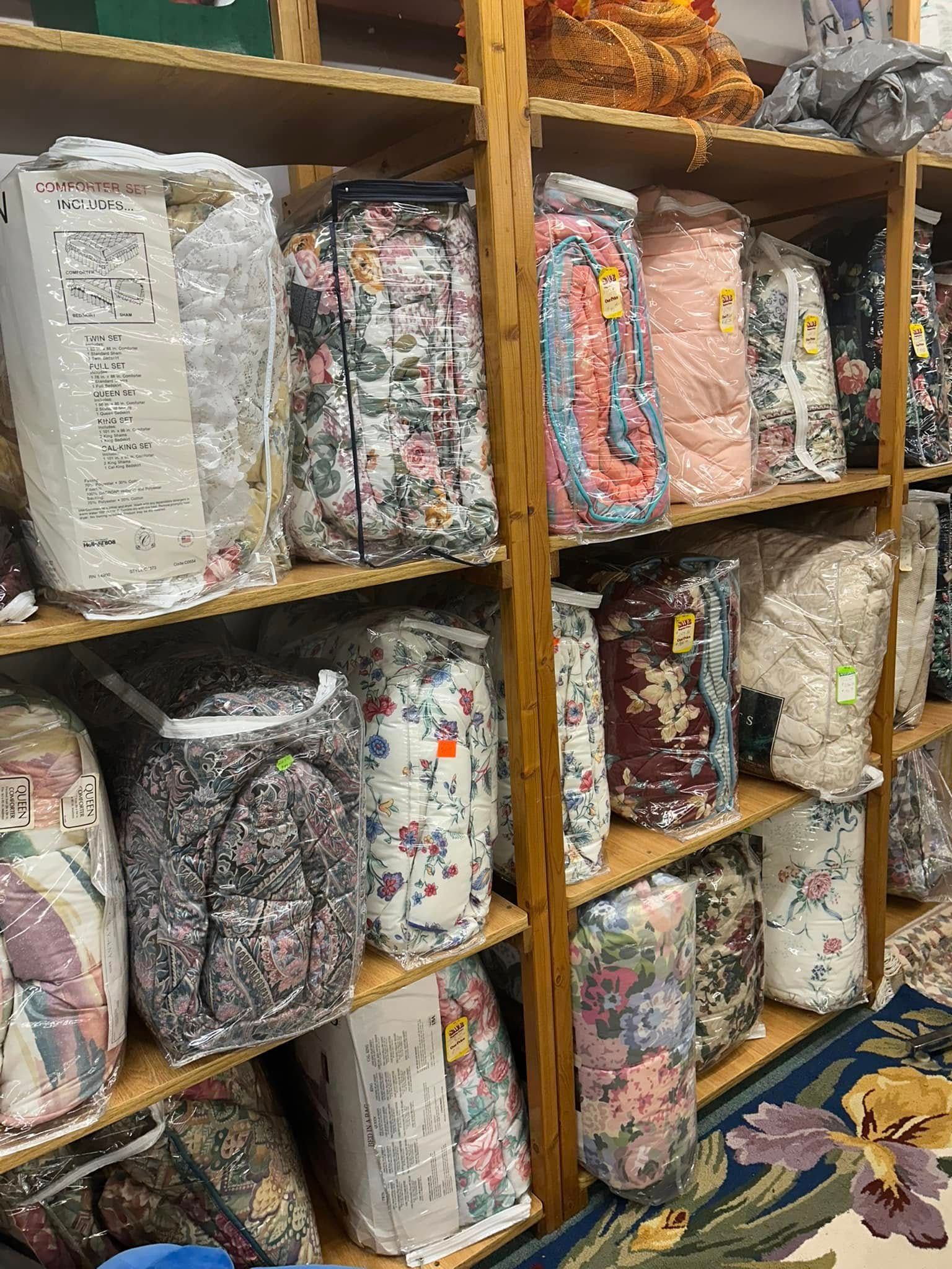 Stacked floral fabric bundles on wooden shelves in a store or textile shop.