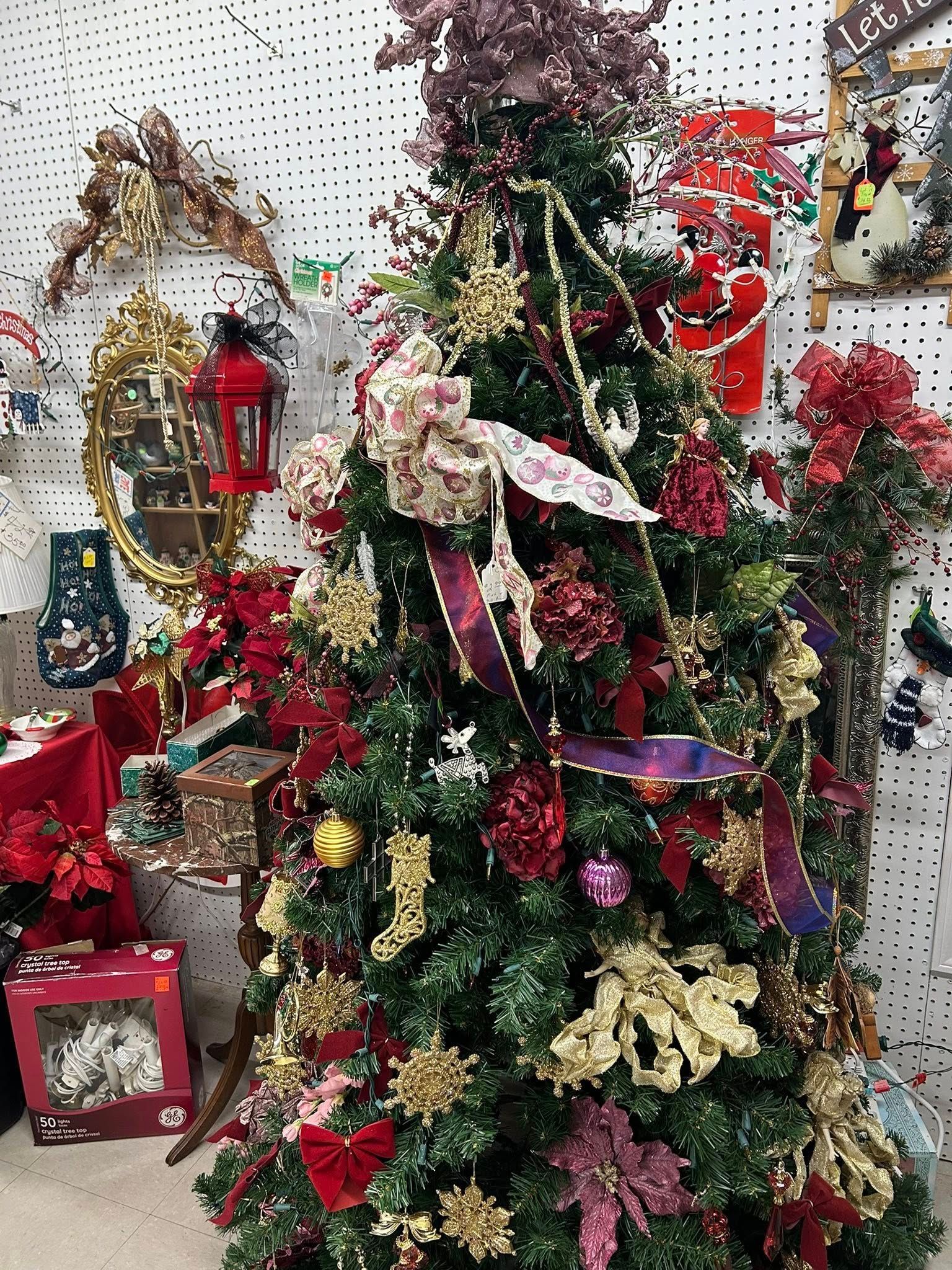 Decorated Christmas tree with red, gold, and white ornaments, ribbons, and lights in a festive indoor display