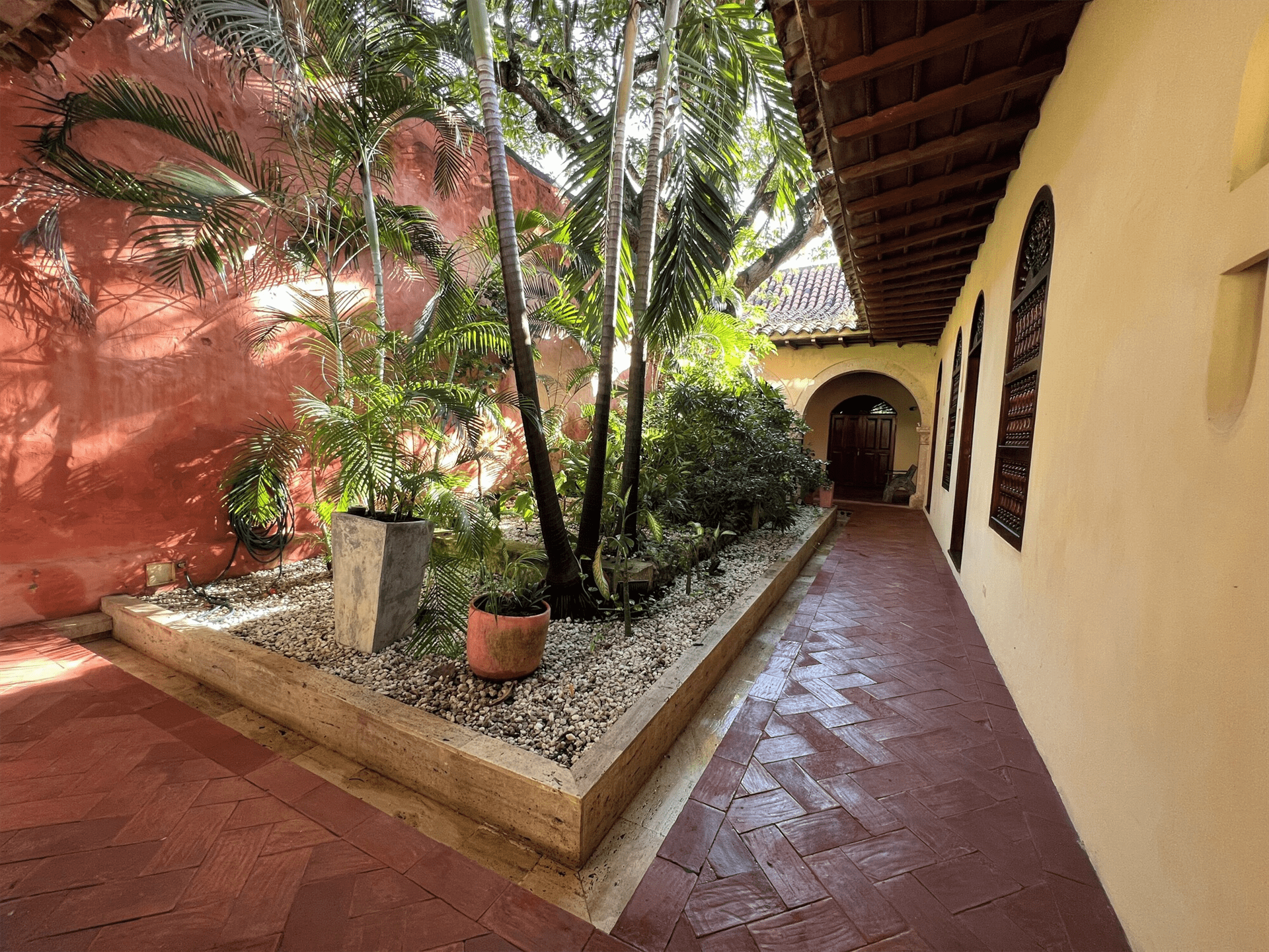 Un largo pasillo que conduce a un edificio con un jardín en el medio. Casa Pierre