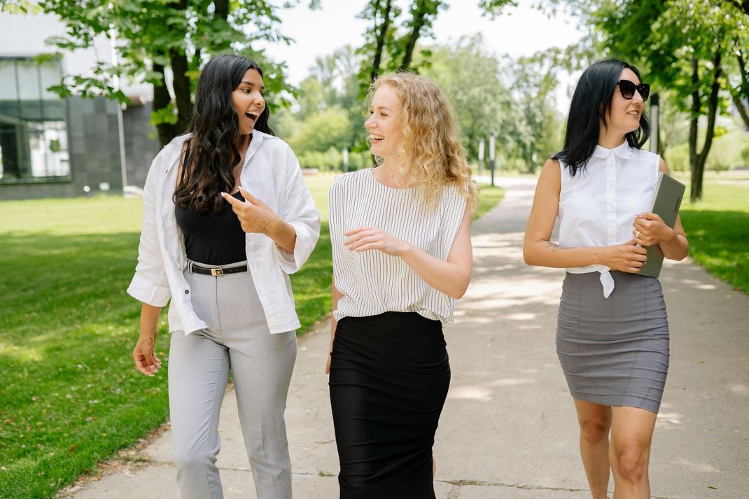 Three women laughing and walking outside.