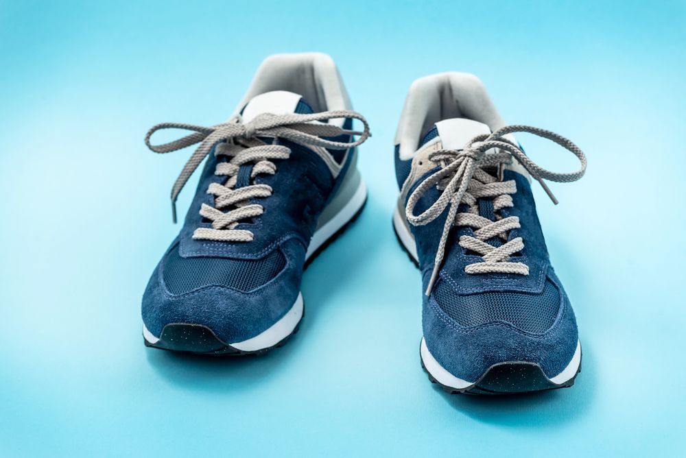 Zapatillas de color azul marino con cordones grises sobre fondo azul.