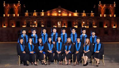 Un grupo de graduados posan para una fotografía frente a un edificio