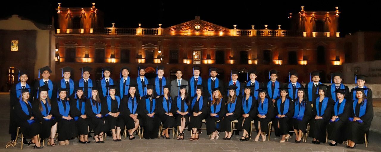 Un grupo de personas está parado frente a un edificio por la noche.