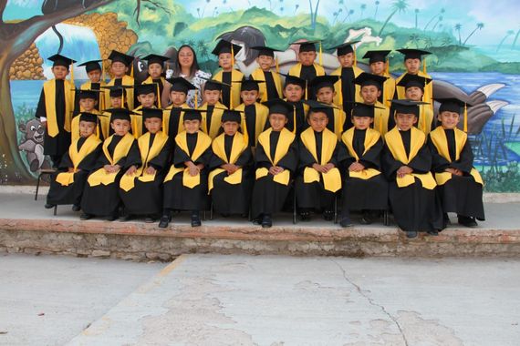 Un grupo de niños con togas y birretes de graduación posan para una fotografía