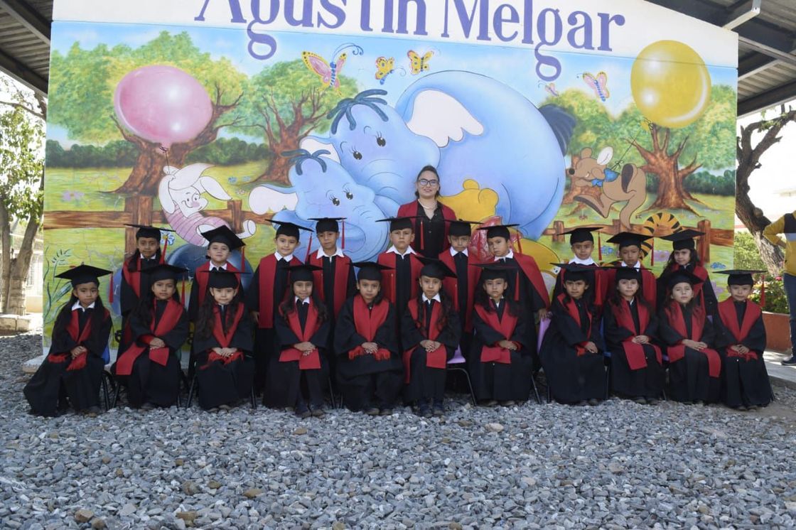 Un grupo de niños con togas y birretes de graduación posan para una fotografía