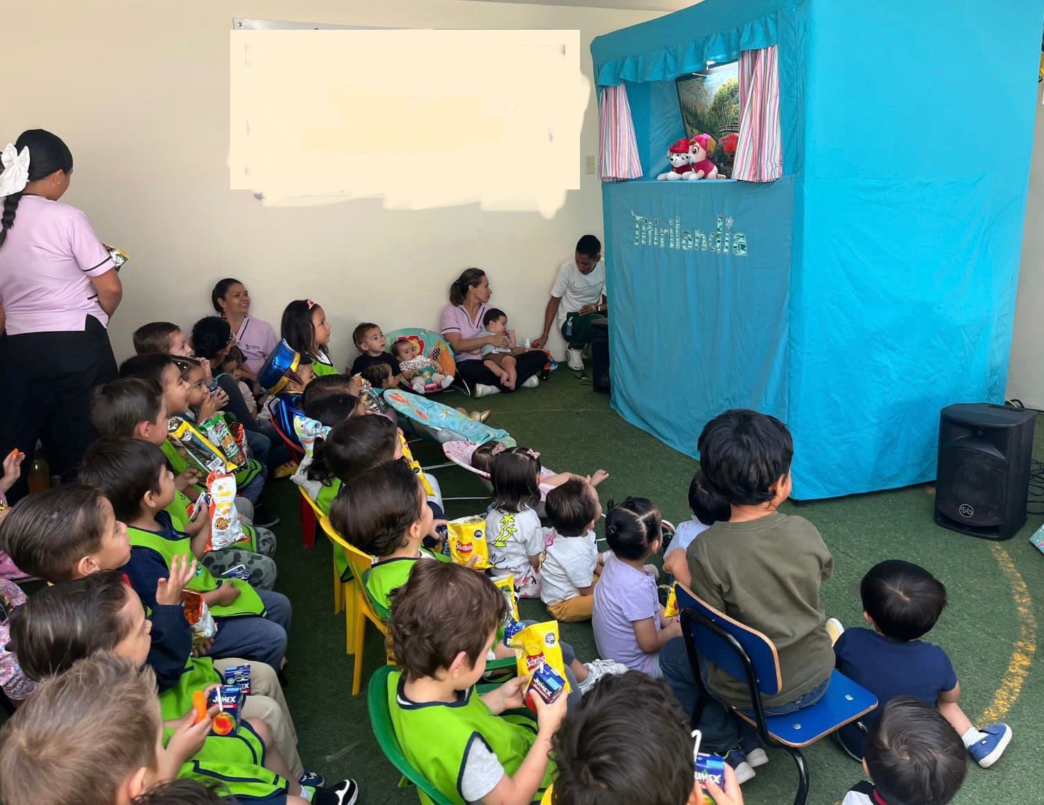 Un grupo de niños está sentado frente a un espectáculo de marionetas.