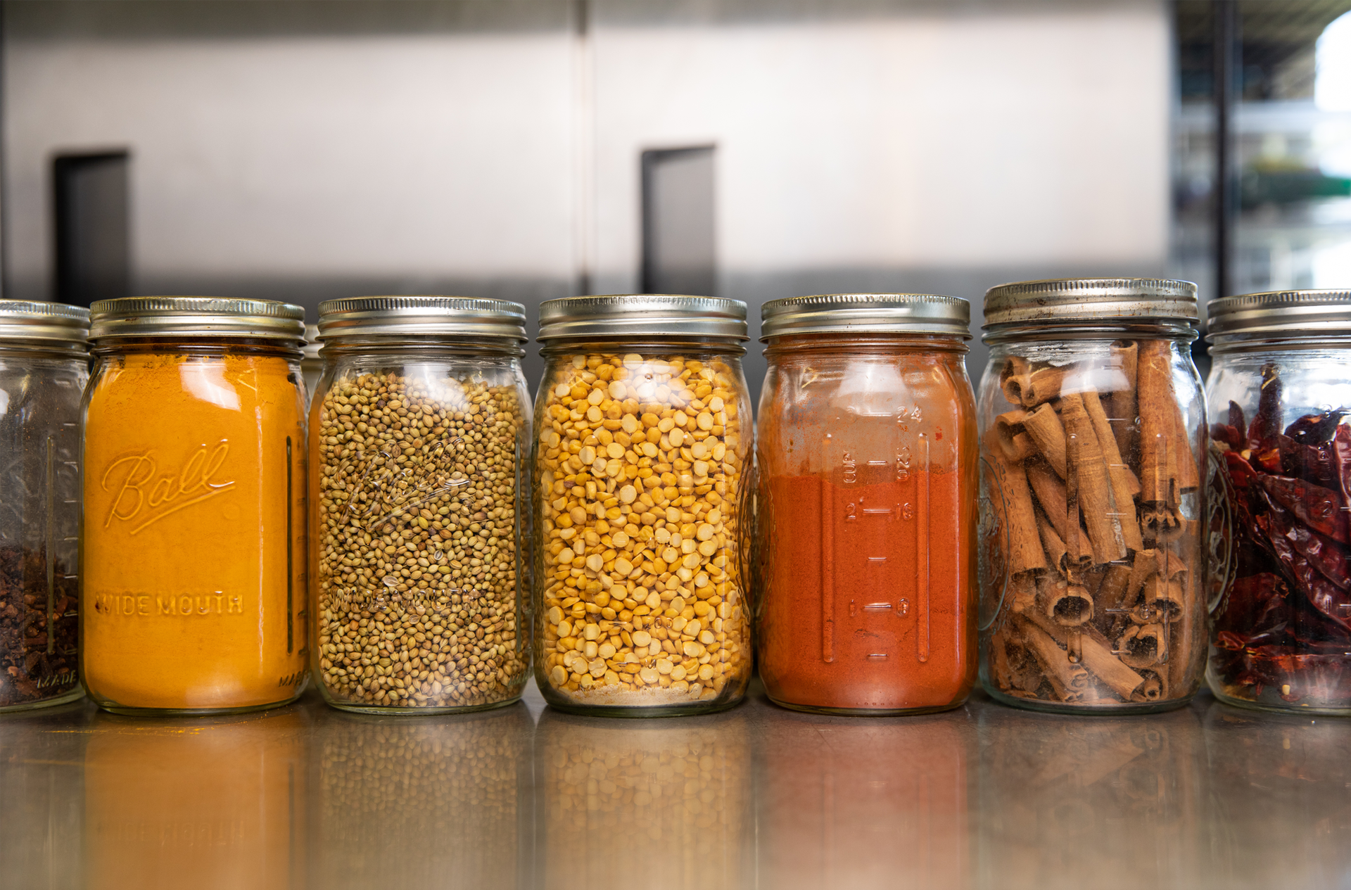 A row of jars filled with different types of spices on a counter.