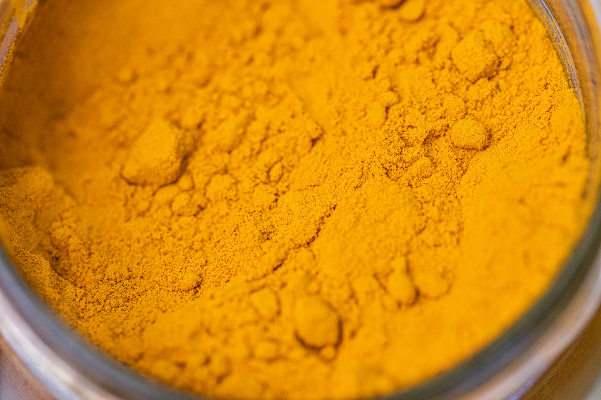A close up of a jar of turmeric powder on a table.