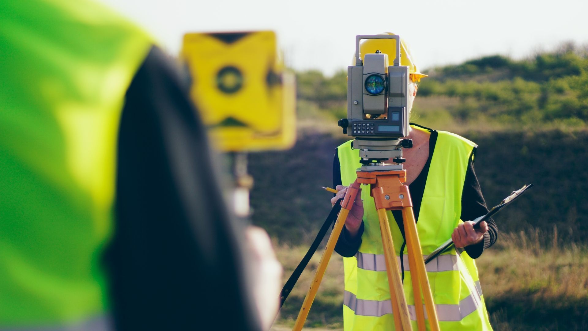 Showcasing What is Land Surveying by showing two engineers on a site taking measurements.