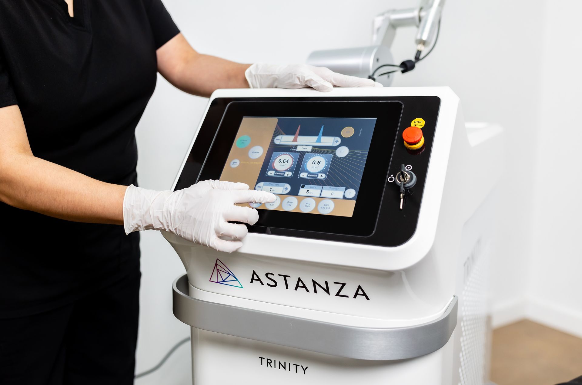 Person in gloves operating an Astanza Trinity laser machine, touching the touchscreen interface.