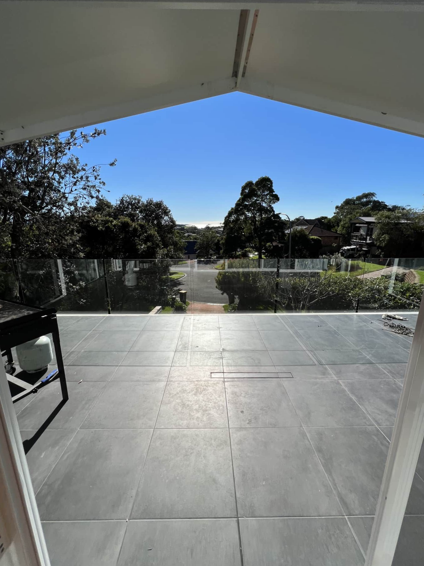 A View From Inside a Doorway Looking Out at a Paved Grey Patio — Taddeo Constructions in Gerringong, NSW