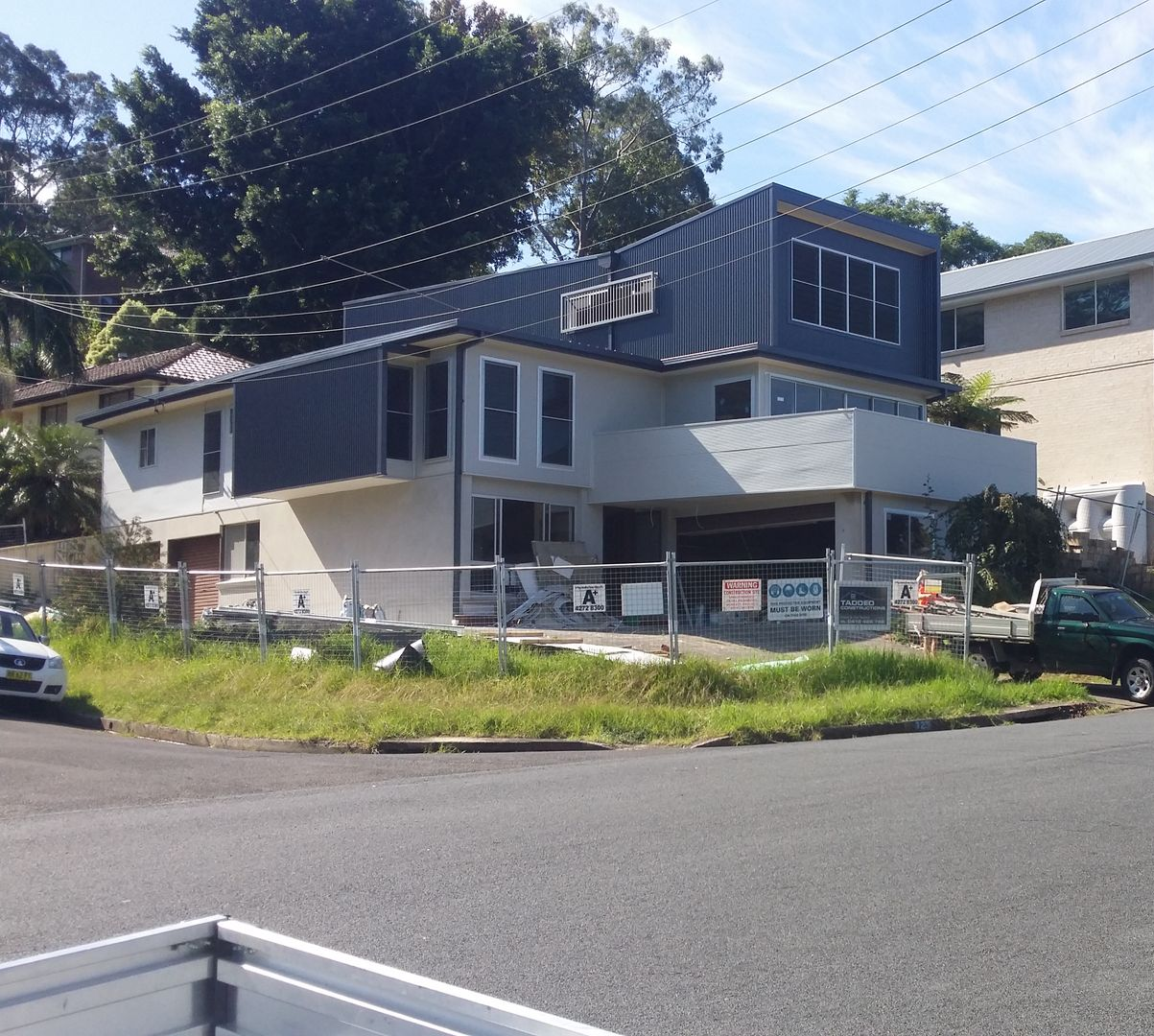 Modern two-story house with blue siding on a sunny street corner, viewed from across the road. — Taddeo Constructions in Kiama Downs, NSW