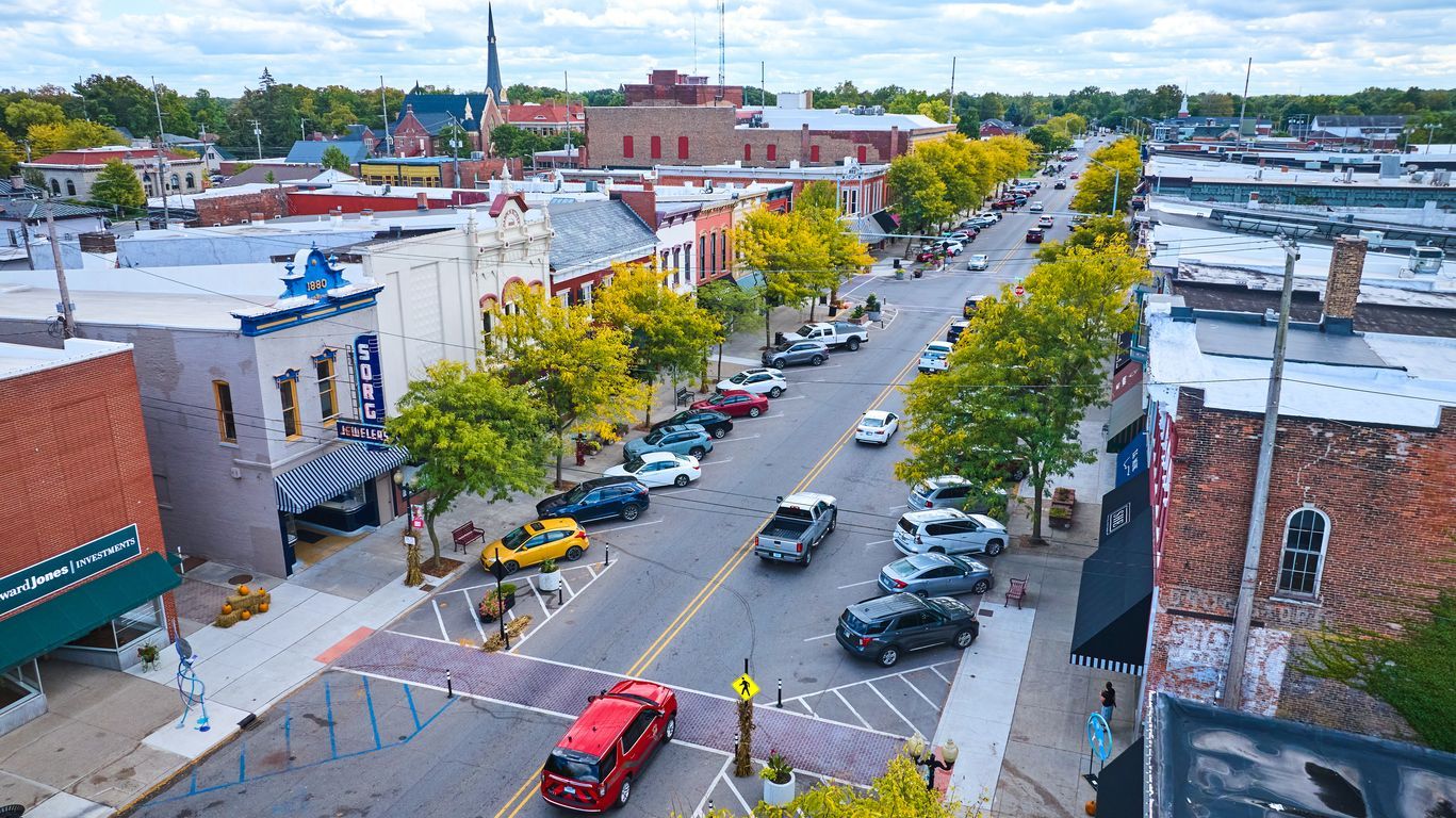 A picture of a small town with a traditional main street. Cars are driving through it.