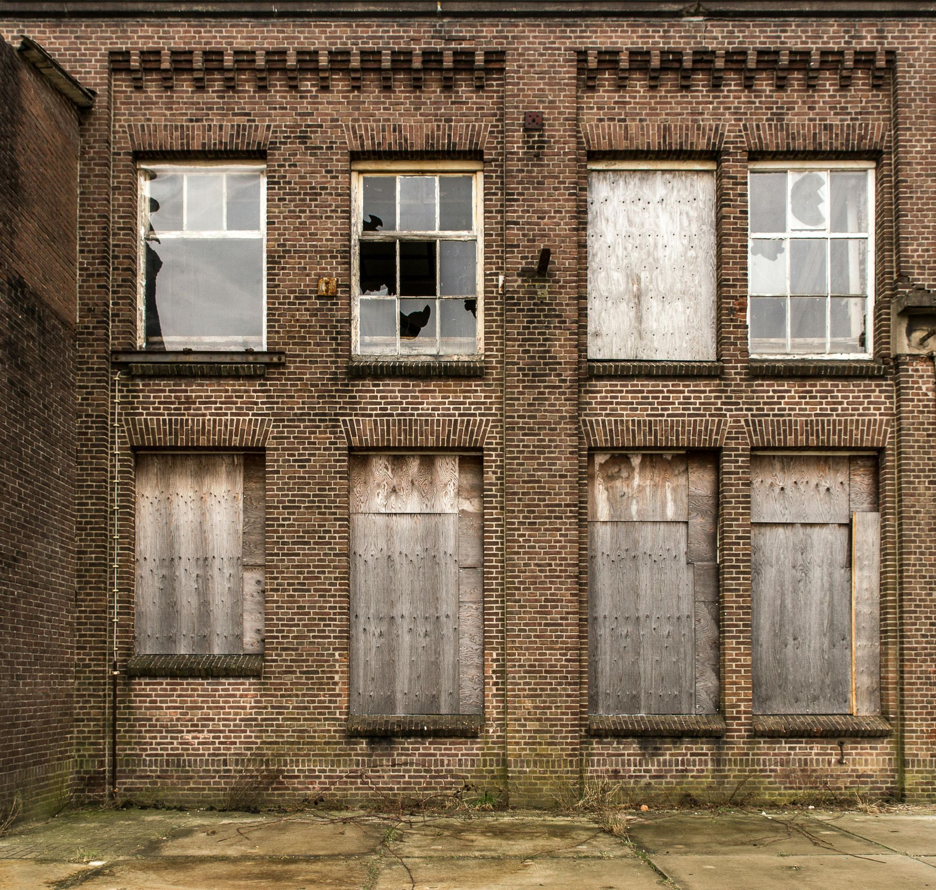 A brick building with broken and boarded-up windows.