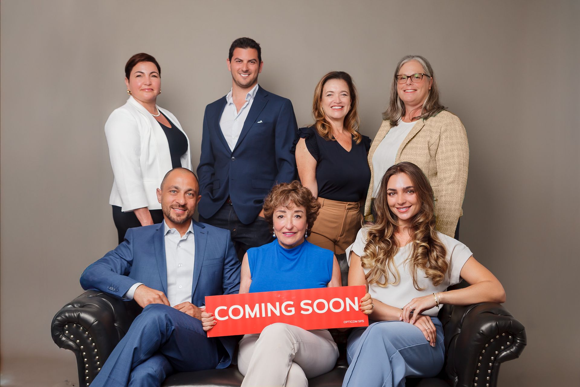 Real Estate office branding photo taken on grey brackground. Agents are wearing coordinated colors that represent the company.