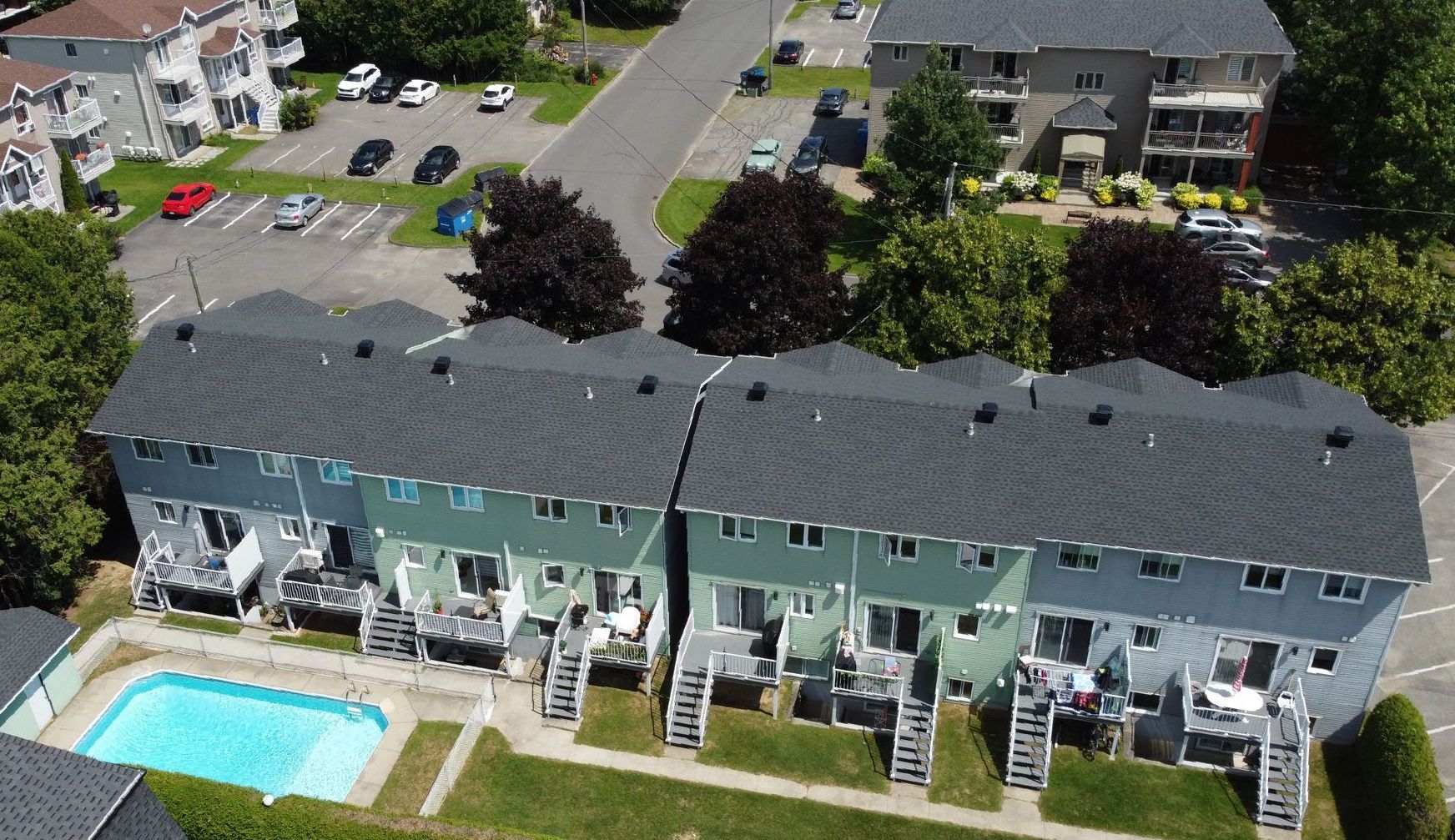 Rangée de maisons de ville avec piscine, stationnement et arbres.