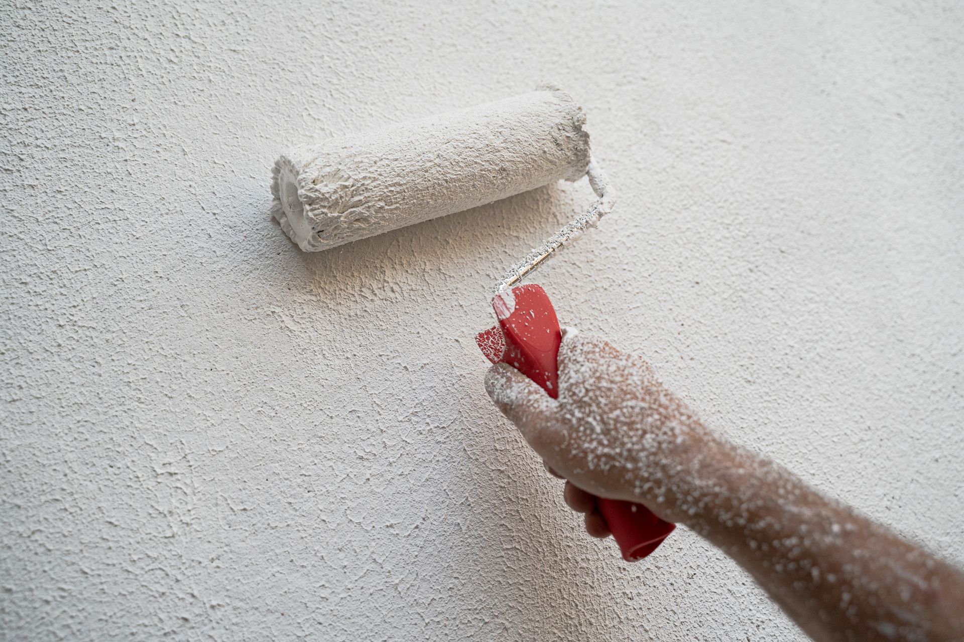 a person is painting a wall with a paint roller