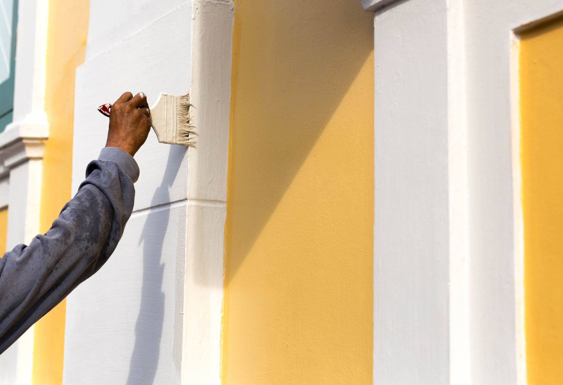 a man paints a yellow and white wall with a brush