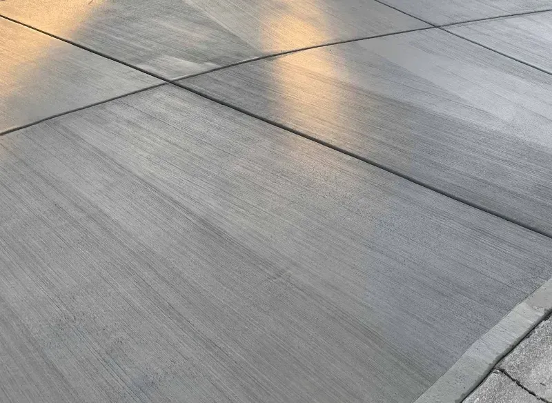 Gray concrete surface with grid of lines, reflecting sunlight.