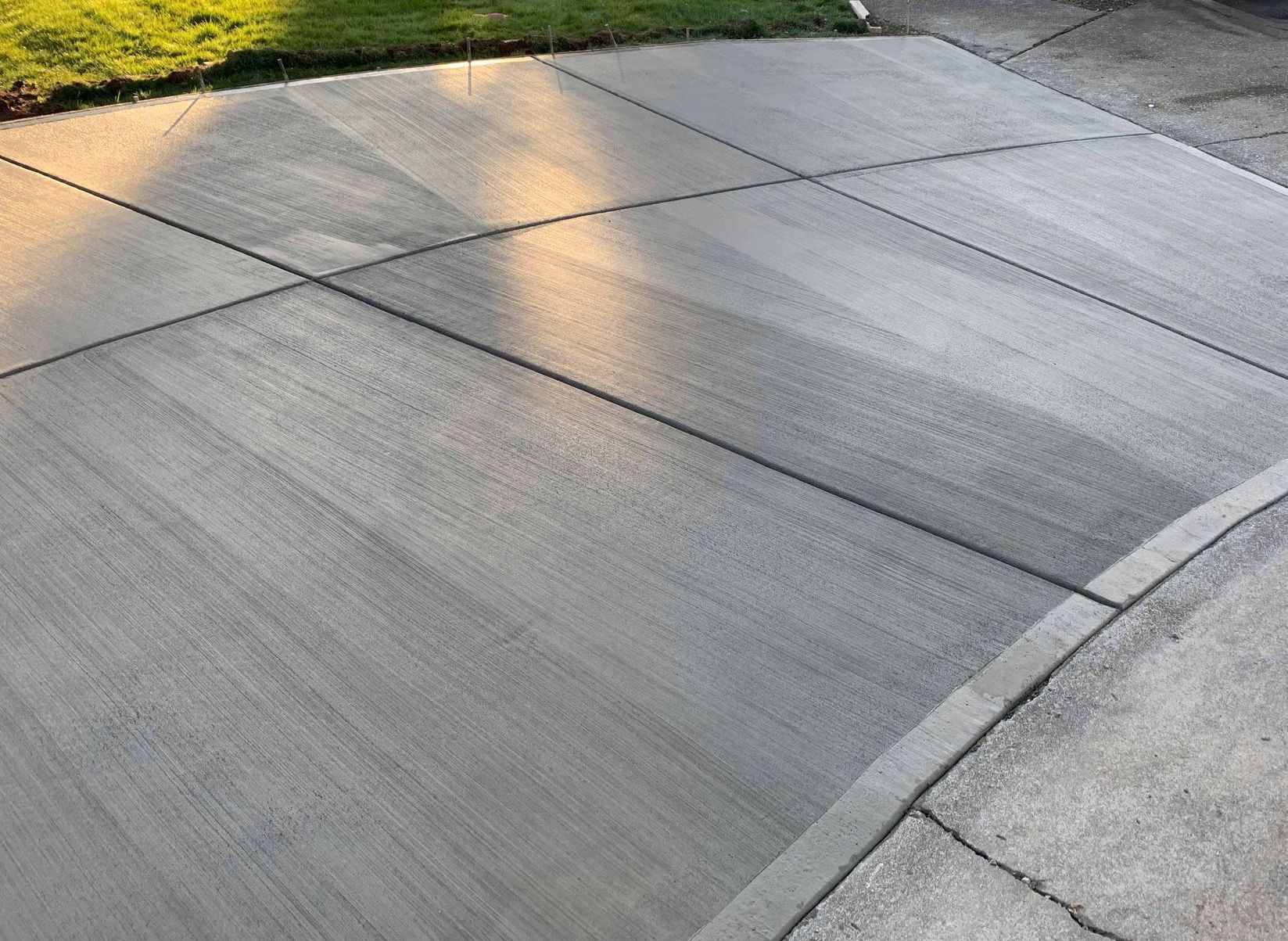 A concrete driveway with a curb and grass in the background in Portland OR