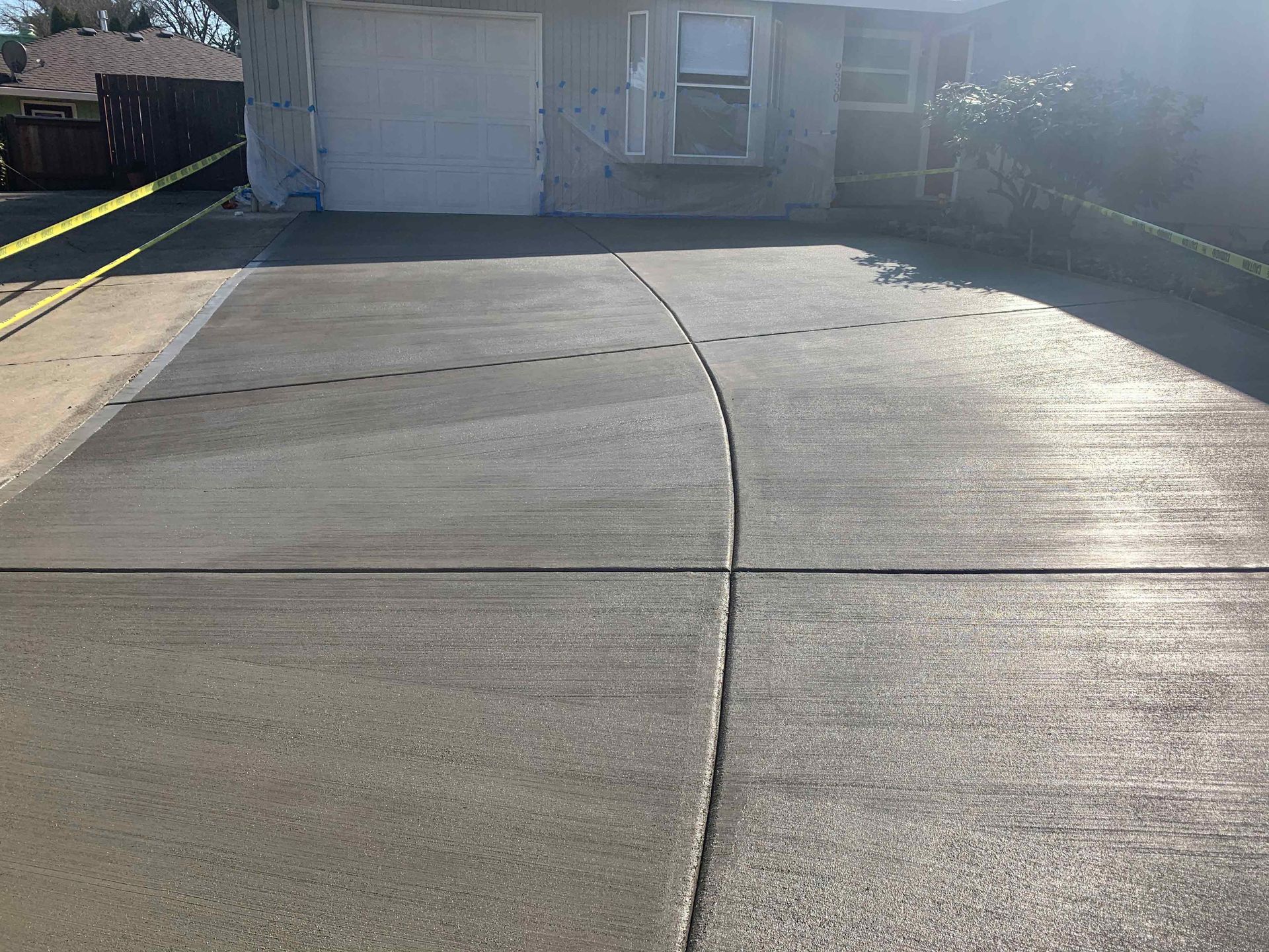 Freshly poured concrete driveway in front of a house with a closed garage door.