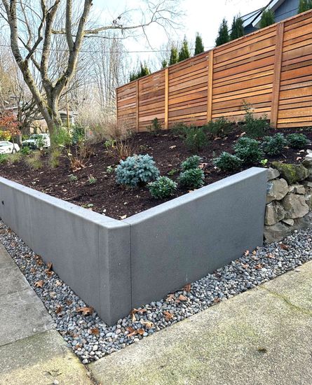 a garden with a wooden fence and a concrete wall surrounding it .