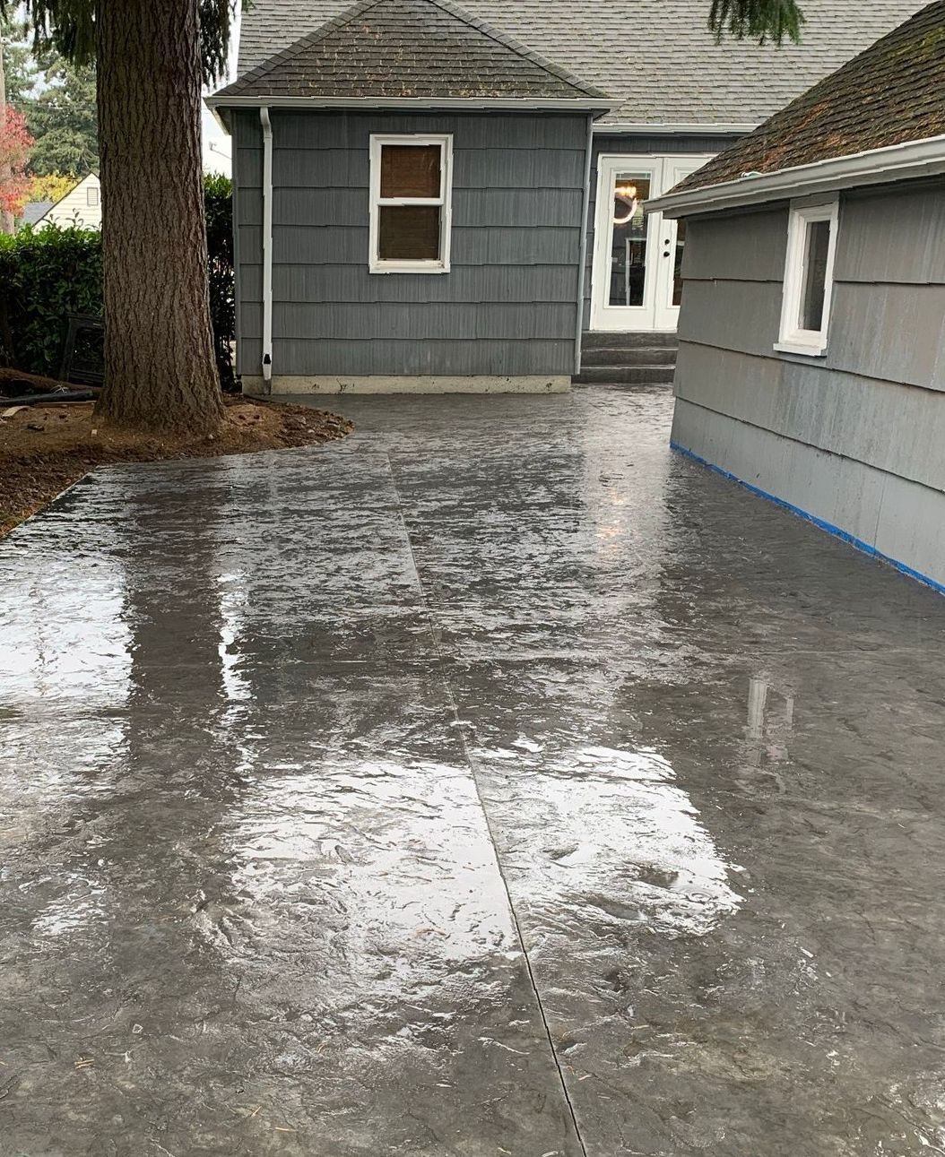 a driveway with a house in the background and a tree in the foreground in Portland OR