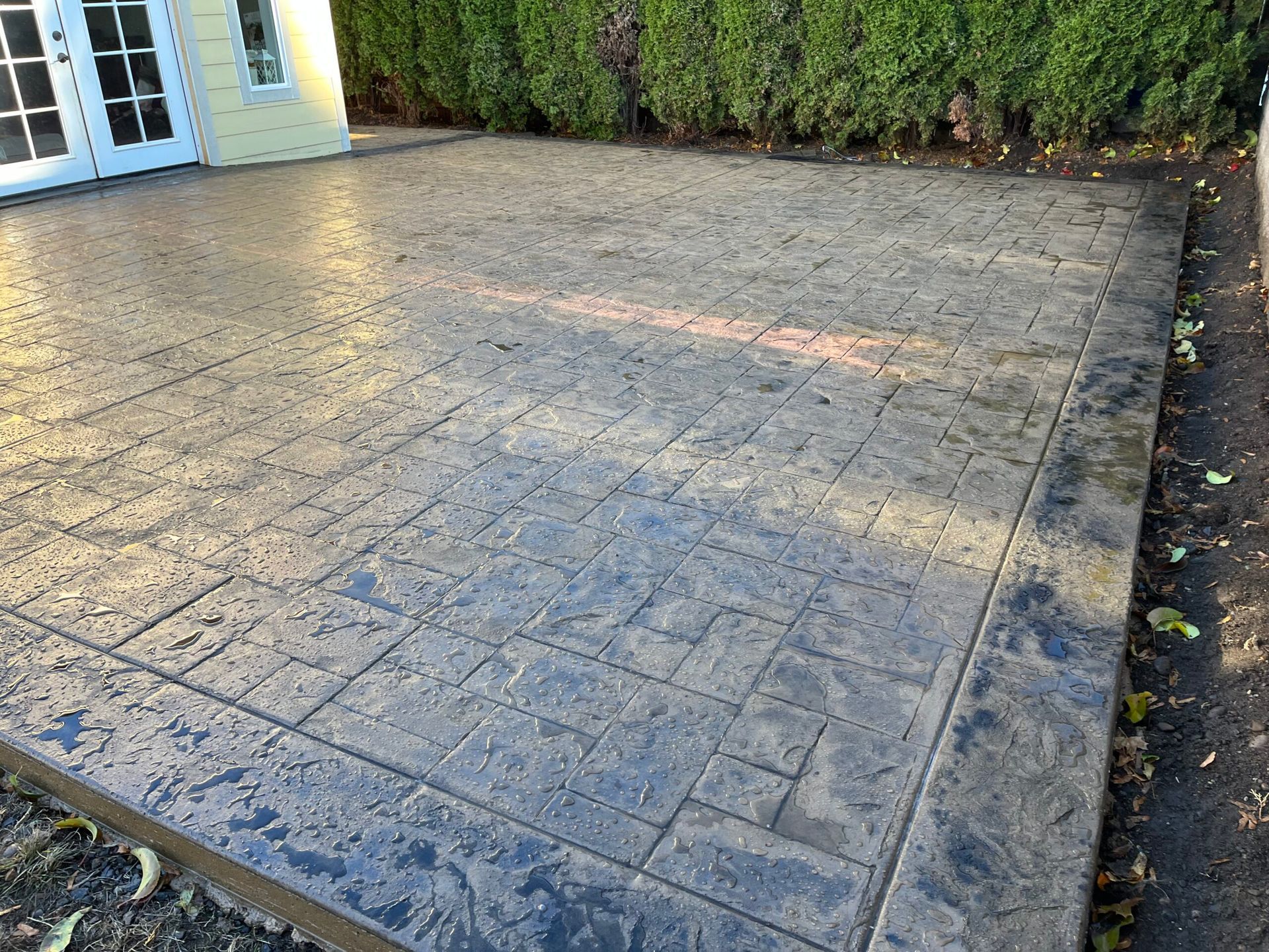 A Concrete patio with a brick pattern and a white house in Portland OR