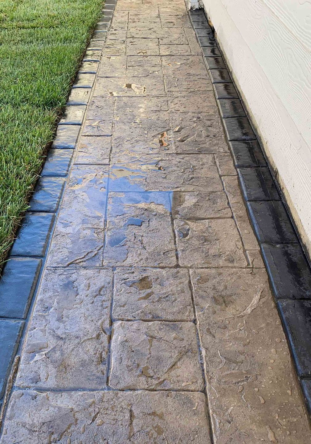 a stone walkway leading to a house next to a lush green lawn .