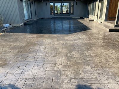 A concrete driveway in front of a house with a large window.