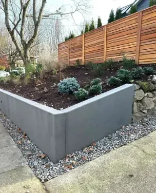 A garden with a wooden fence and a concrete wall
