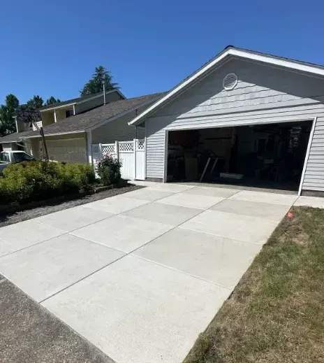 A concrete driveway in front of a house with a white garage door.